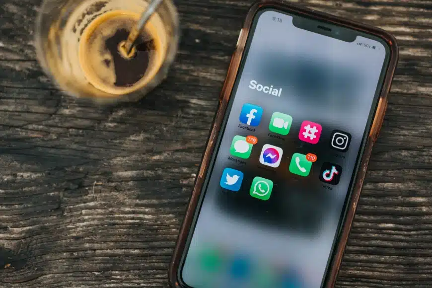 tasse de café à côté d'un smartphone affichant les applications des principaux réseaux sociaux